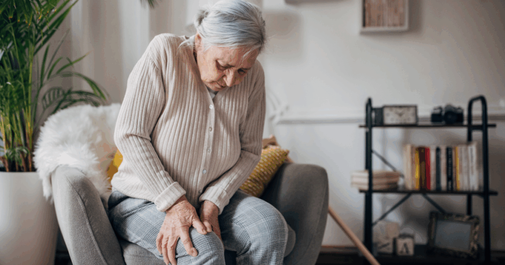 ऑस्टियोआर्थराइटिस से पीड़ित महिला घुटनों को पकड़े हुए